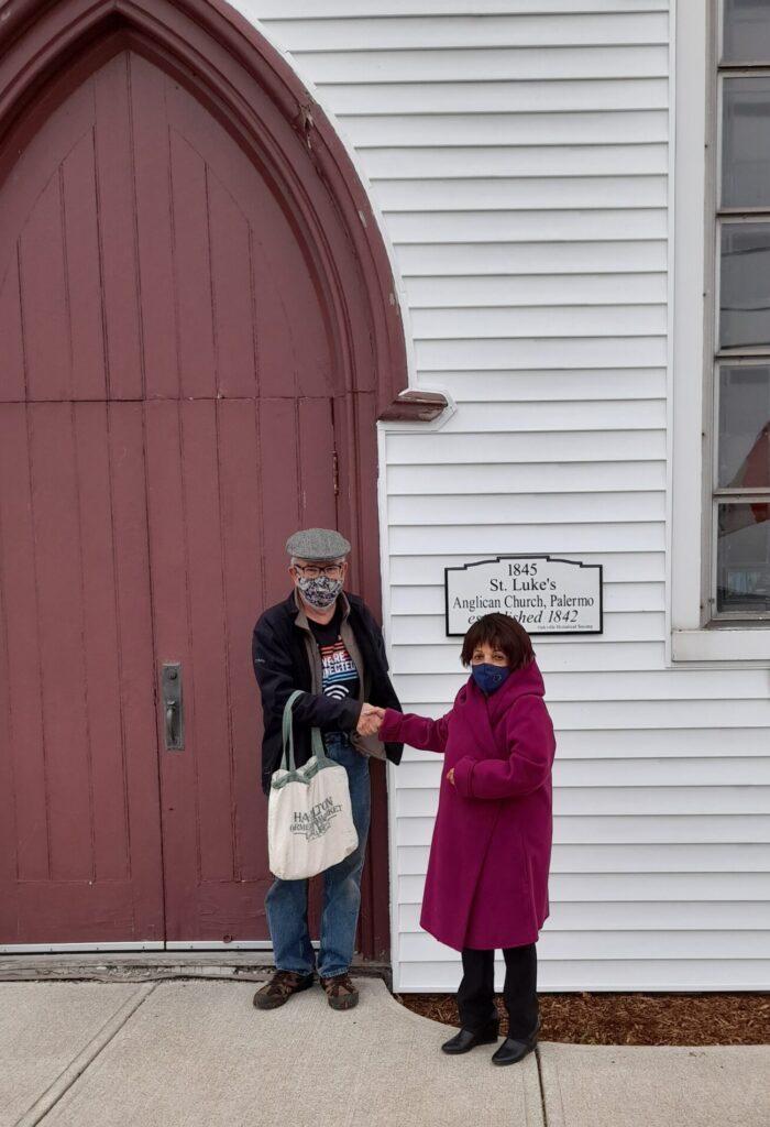 George Chisholm presents the Oakville Historical Society's plaque to Gladis Di Paolo in front of St. Luke's historic church building.